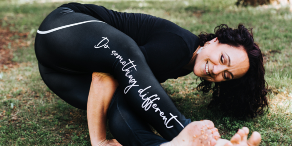 A person doing yoga. Their leggings have "Do something different" written along the leg.